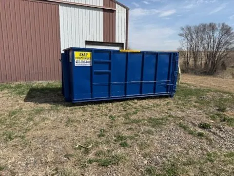 A large blue ASAP Containers roll-off dumpster delivered on site