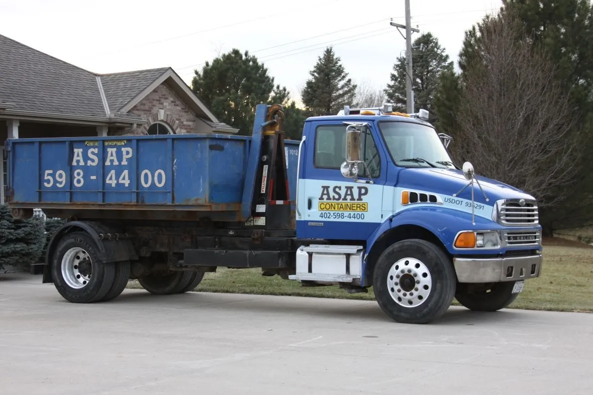 A blue ASAP Containers roll-off dumpster on a job site in Omaha, NE